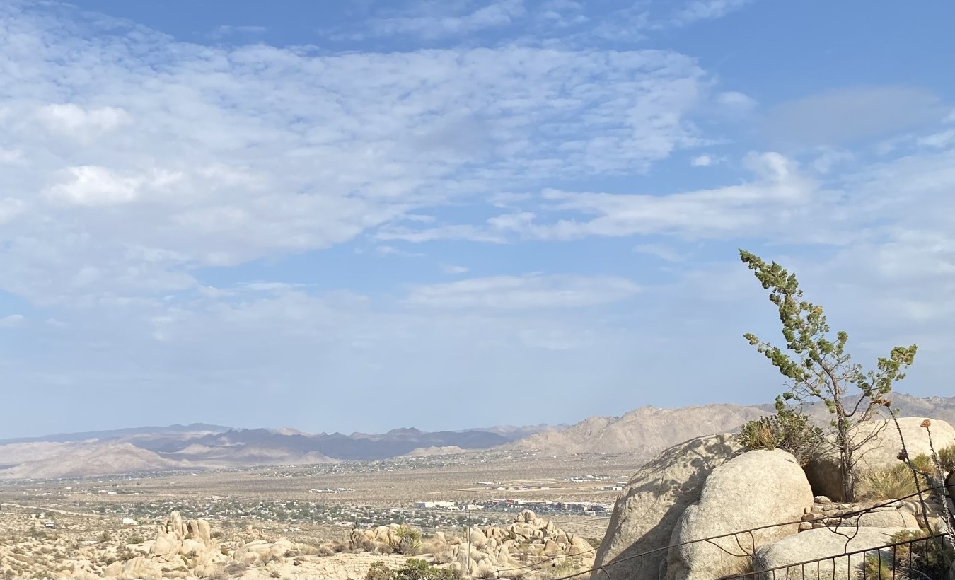High-desert landscape: a lone tree growing from granite boulders above a town in the valley below